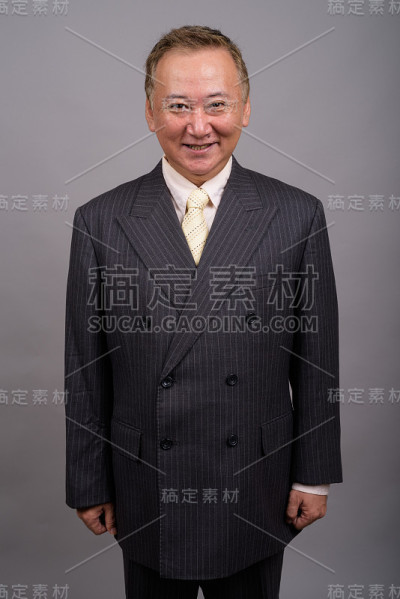 在灰色背景下拍摄成熟的亚洲商人