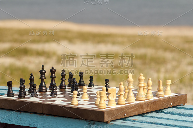 棋盘与棋子放在河堤上的木凳上