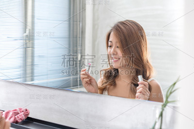 近距离的微笑女人化妆刷近脸和看镜子。亚洲美女