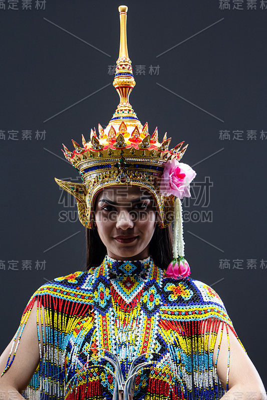 美丽的女人穿着泰国南方民族舞蹈服装，用五颜六色的珠子，把头饰在她的头上，模特摆姿势在坚实的背景