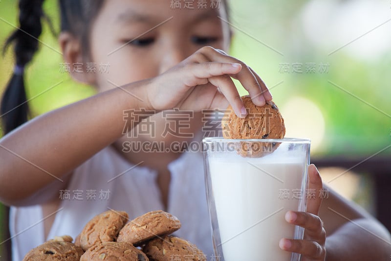 可爱的亚洲小女孩吃饼干和牛奶的早餐幸福