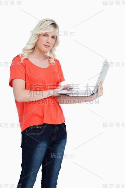 一个严肃的金发女人左手拿着笔记本电脑