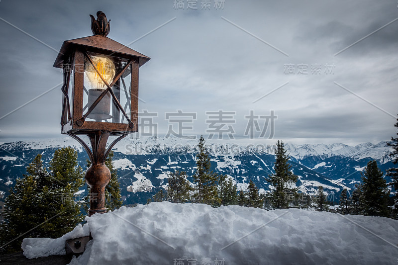 老灯笼立在栏杆上，背景是白雪皑皑的群山