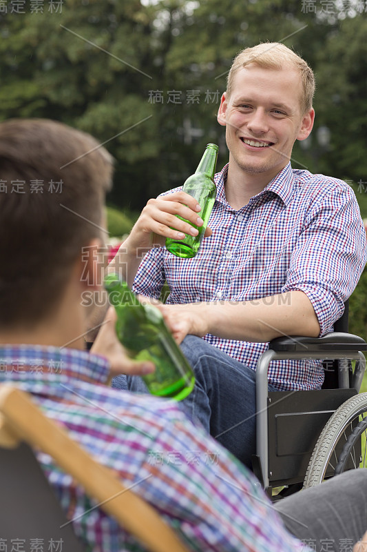 坐在轮椅上和朋友喝啤酒的男人