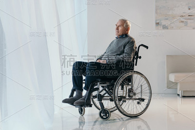 坐在轮椅上沉思的老男人向窗外望去