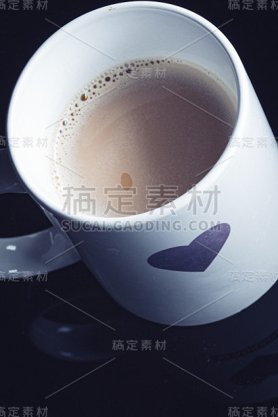 心形画在一个白色的咖啡杯上的黑色表面背景