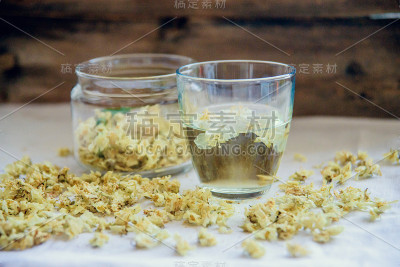 绿色背景木桌上的茉莉花绿茶杯和茶壶