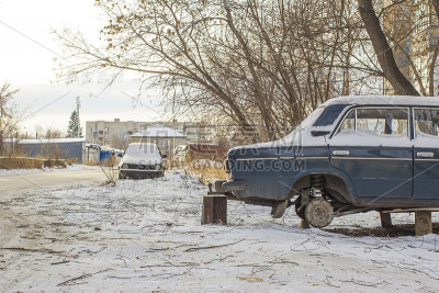 蓝色的汽车与移走的联合车轮在一个潮湿的房子在雪地上