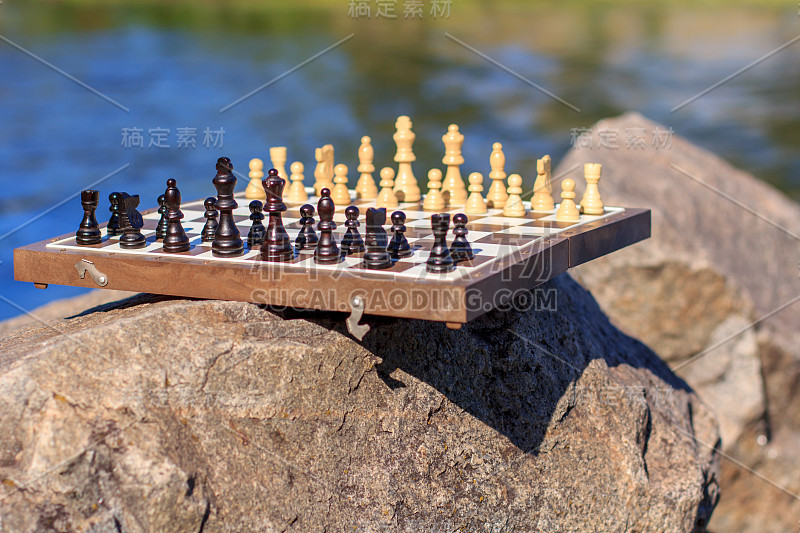 棋盘与棋子在岩石与河流的背景