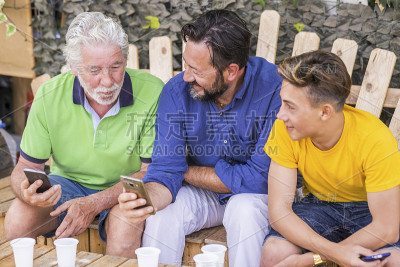 一代又一代的男人和祖父、父亲、儿子、侄子从老到年轻呆在一起，使用蜂窝技术智能手机连接到互联网