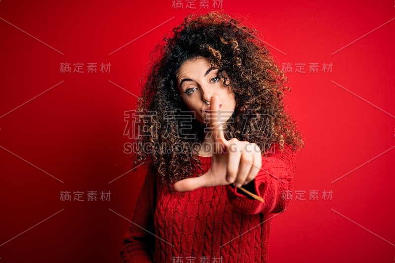 年轻美丽的女人与卷发和穿休闲红色毛衣指向手指和愤怒的表情，显示没有手势