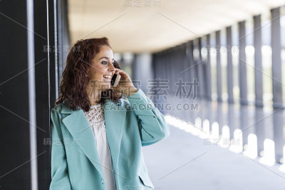 美丽的年轻女子，微笑着和她的手机聊天。在室内