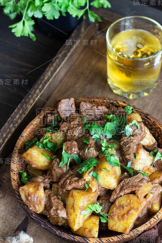 用木盘炖肉、土豆和欧芹。传统的葡萄牙炖肉。木制背景。