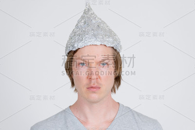 年轻人的脸戴着锡纸帽作为阴谋论的概念