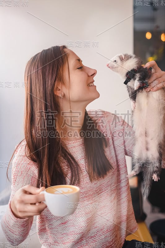 微笑的年轻女子和她的宠物雪貂在咖啡馆