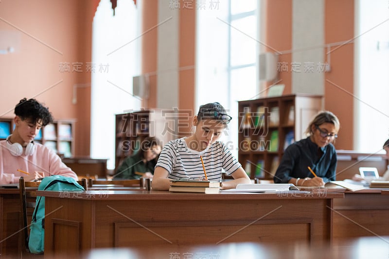 十几岁的女孩和其他大学生在抄写本上做笔记