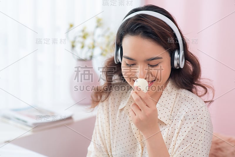 年轻的亚洲女人听音乐喜欢马卡龙