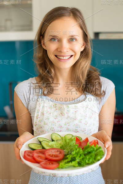 微笑的女人拿着盛着切片蔬菜的盘子