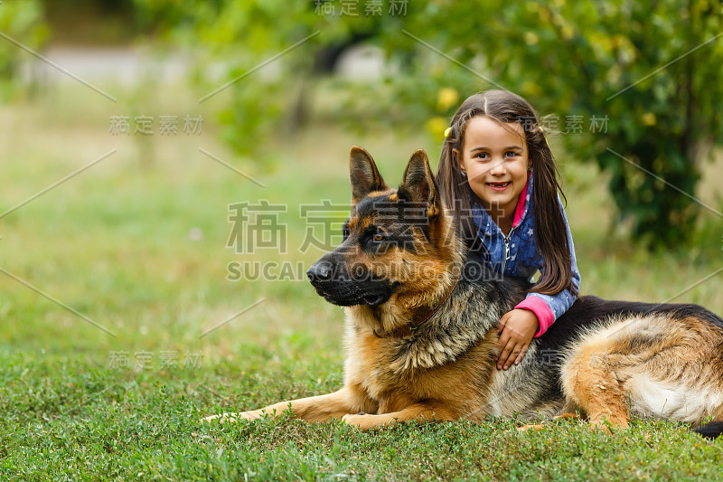 漂亮的小女孩，命令德国牧羊犬坐下。