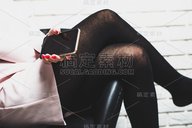 一位坐在椅子上的女士手里拿着一部手机，正对着摄像头。