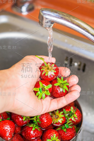 熟透的有机草莓在厨房的自来水下