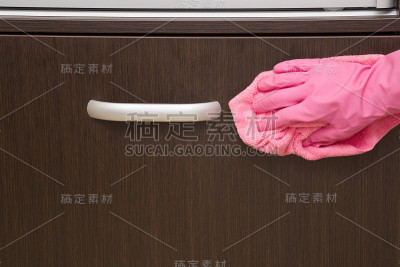 手戴橡胶防护手套，用超细纤维抹布擦拭室内木制家具上的指纹。早春大扫除或定期大扫除。女仆打扫房子。