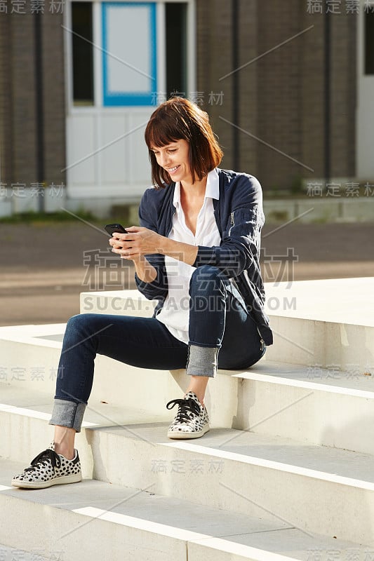 快乐的老女人坐在台阶上拿着智能手机