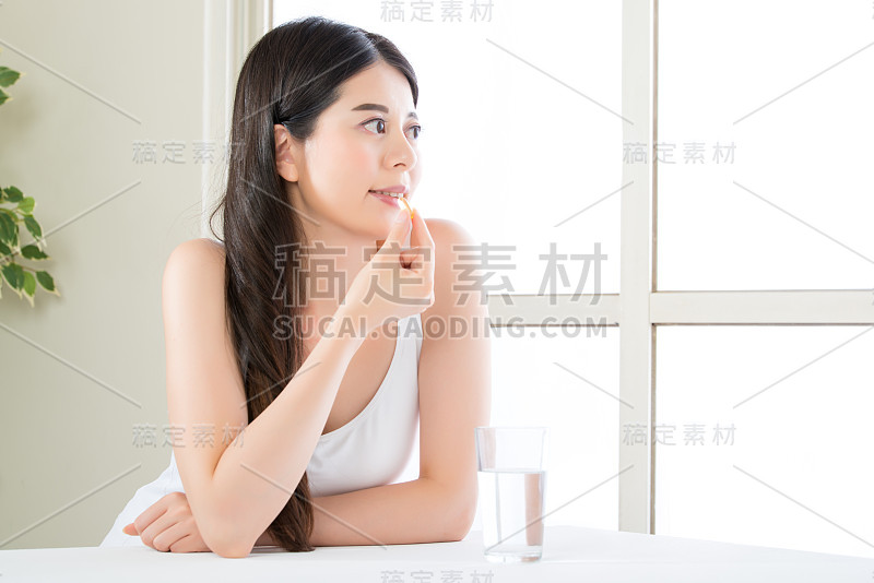 美丽的亚洲女性食用营养鱼油补充剂