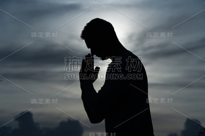 男人的剪影祈祷在日落。宗教、信仰和希望的观念