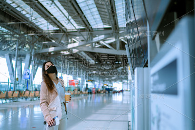 亚洲女商人在机场阅读离境牌。