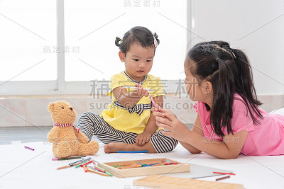 亚洲小女孩和妹妹一起玩，一起画画。小女孩和姐姐一起学画画。