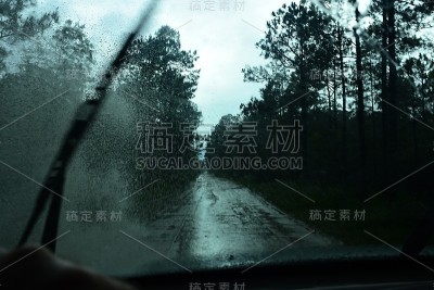 在雨中森林的泥土路上开车时，水从水坑里溅起