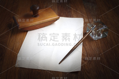 木桌上放着一支带墨水瓶的旧钢笔和一张白纸