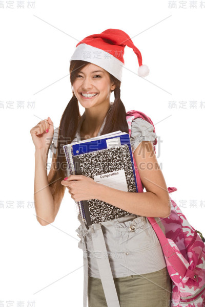 亚洲学生女孩在圣诞老人帽与作文书