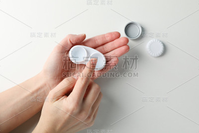 女人从隐形眼镜盒白色背景，俯视图