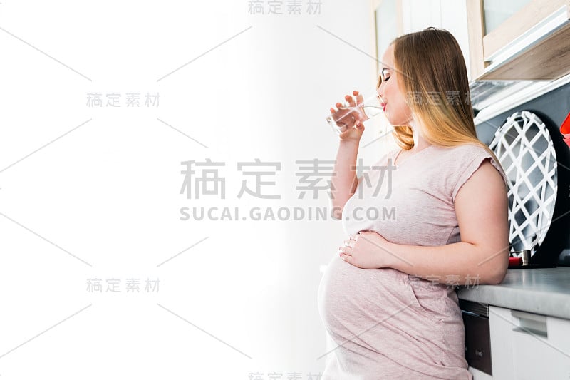 孕妇在厨房饮用淡水，孕期保健概念