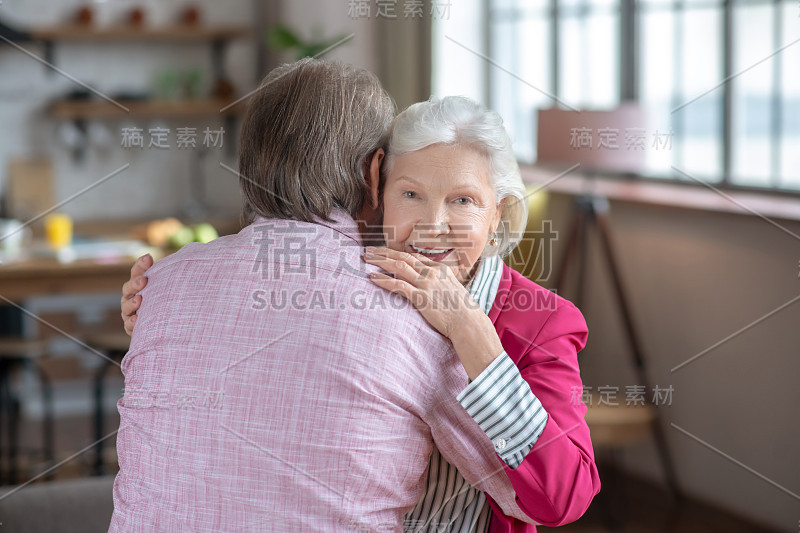 灰白头发的女人拥抱着她的丈夫，感到幸福