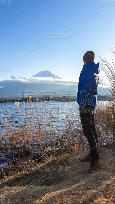 日本——一名男子站在川口湖边，眺望富士山