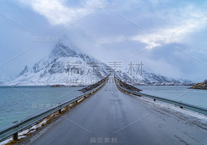 欧洲挪威诺德兰郡罗弗敦群岛的弗雷德旺大桥和公路。白雪皑皑的山峦和树木，是冬季自然景观的背景。著名的旅