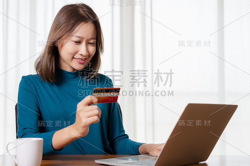 快乐的亚洲女人网上购物和支付信用卡。科技及电子商务概念