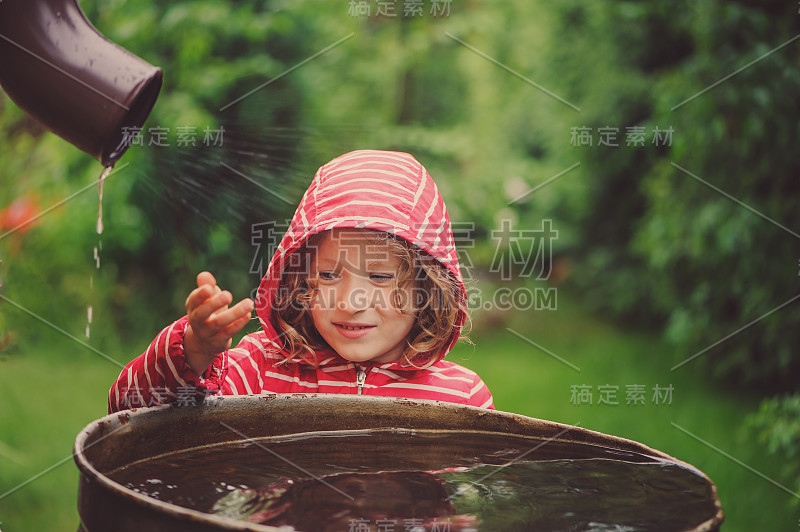 小女孩在多雨的夏日花园里玩水桶