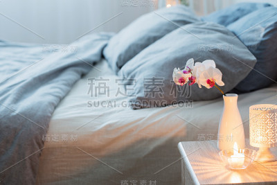 花瓶里插着兰花，白色卧室里点着蜡烛