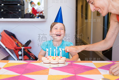 小孩笑着，女人在生日蛋糕上点蜡烛