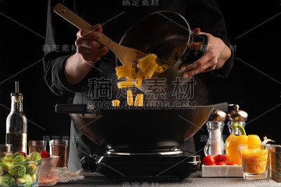 厨师将意大利面与酱汁、蔬菜和肉放在平底锅中煎炸，并撒上调味料。冻结。美味健康的食物。蔬菜和肉。餐饮酒
