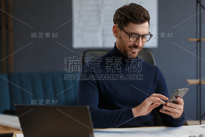 年轻人微笑着用智能手机。快乐的商人使用手机应用程序，发短信，浏览互联网，看智能手机。年轻人使用移动设