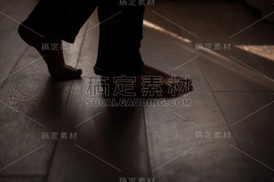 女人的腿放在温暖的木地板上