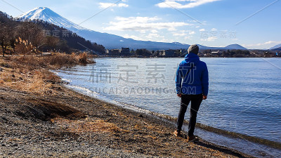 日本——一名男子站在川口湖边，眺望富士山