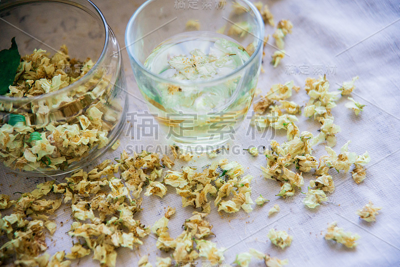 绿色背景木桌上的茉莉花绿茶杯和茶壶