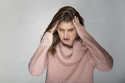 一个年轻女性的肖像穿着粉红色的毛衣看起来犹豫不决和困惑