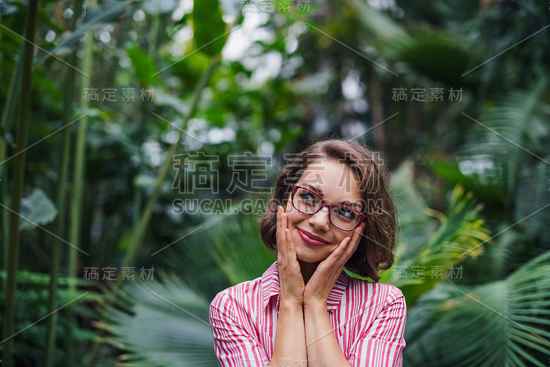 年轻女子站在植物园里。副本的空间。